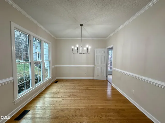 a view of an empty room with window and chandelier fan