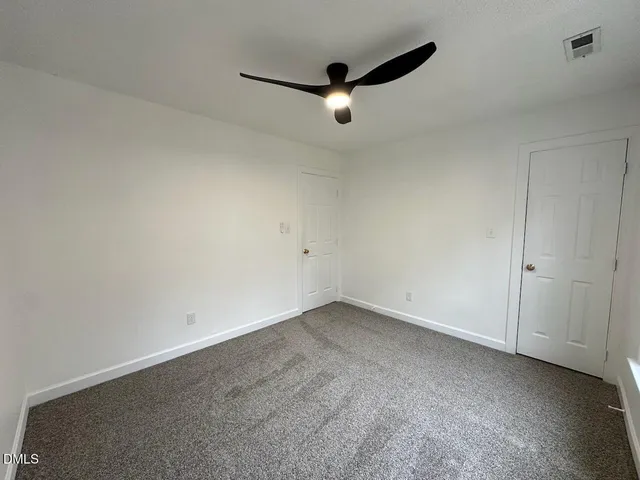 an empty room with a ceiling fan and window
