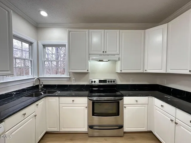 a kitchen with granite countertop white cabinets and black appliances