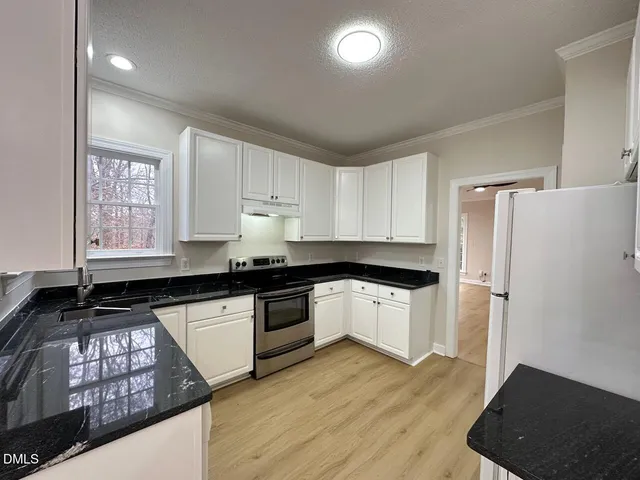 a kitchen with granite countertop a refrigerator stove and sink