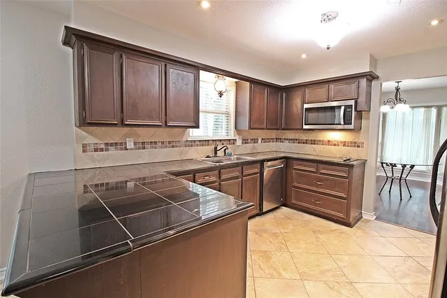a kitchen with stainless steel appliances granite countertop a stove top oven a sink a counter space and cabinets