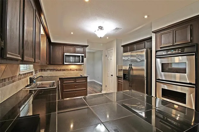 a kitchen with granite countertop a refrigerator and a stove top oven