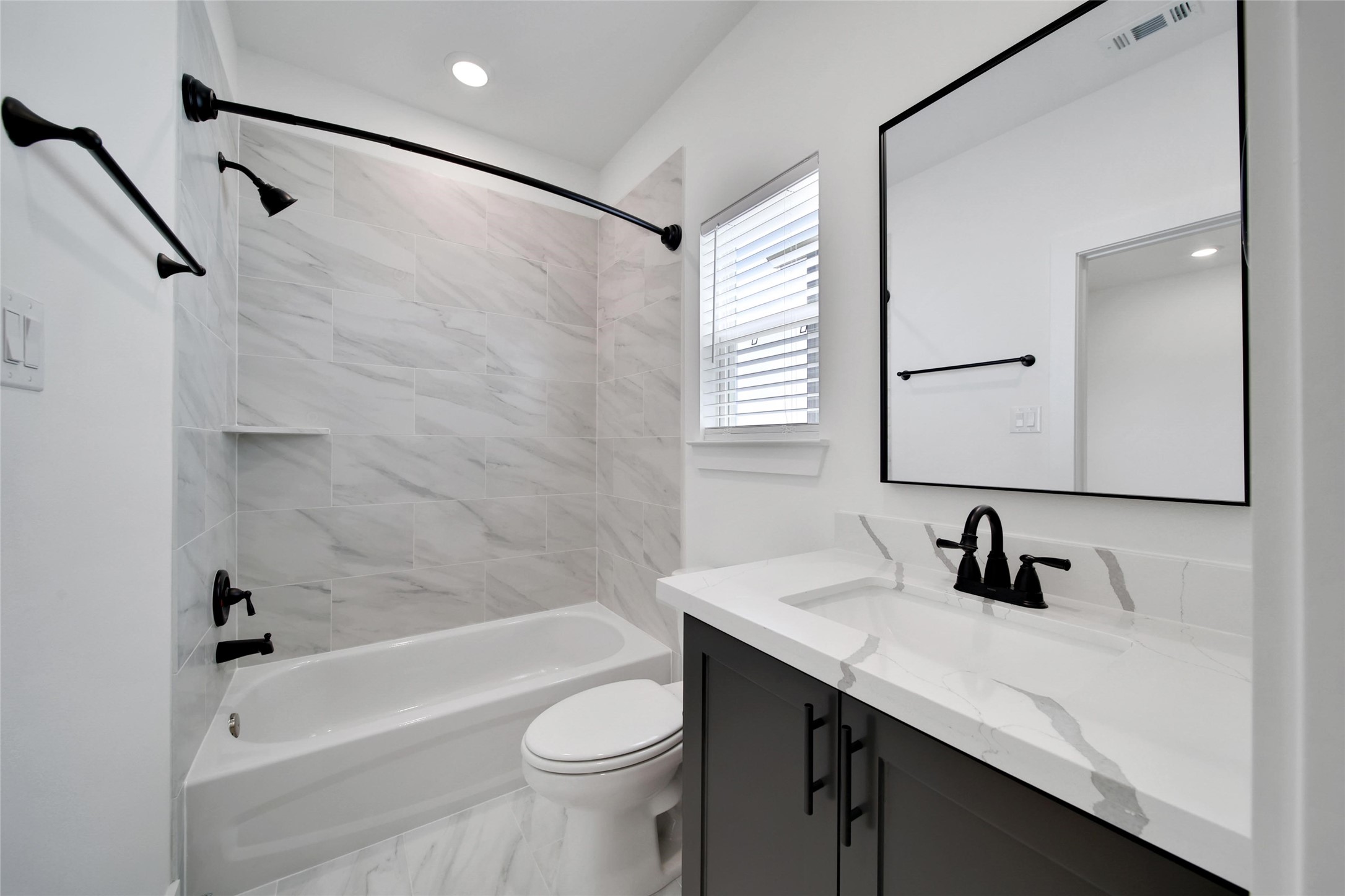 717 Marcella Street, Unit F Houston, TX 77091 - Photo 16 of 37 a bathroom with a sink a toilet a mirror a bathtub and shower