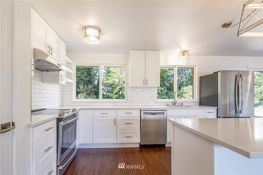 1620 Index Avenue Southeast Renton, WA 98058 - Photo 4 of 39 a kitchen with granite countertop white cabinets white appliances a sink and a large window