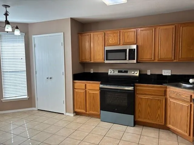 a kitchen with granite countertop white cabinets stainless steel appliances and a window