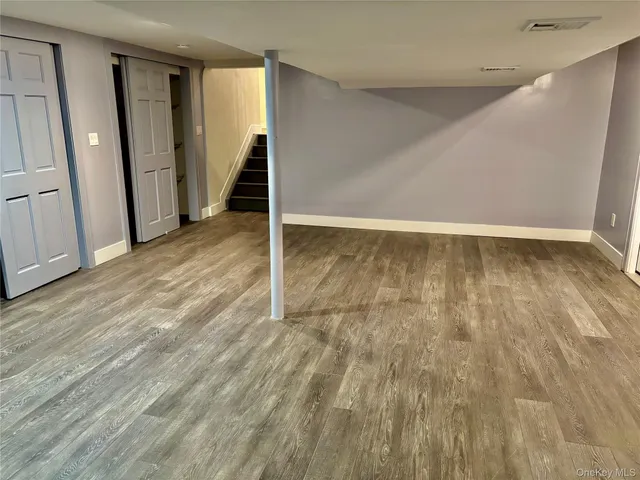 a view of an empty room with wooden floor and stairs