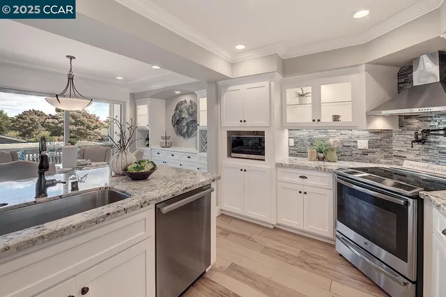 a kitchen with stainless steel appliances granite countertop a stove a sink and a microwave