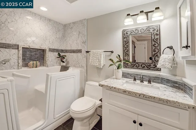 a bathroom with a granite countertop sink vanity mirror and toilet