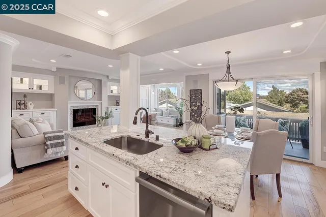 a kitchen with granite countertop a stove a sink a dining table and chairs