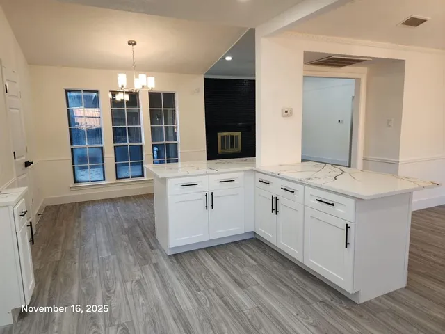 a kitchen with kitchen island granite countertop a stove top oven a sink dishwasher and a refrigerator with wooden floor