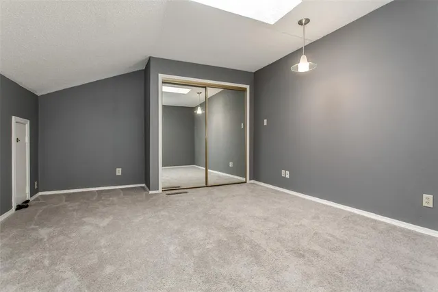 an empty room with wooden floor closet and windows