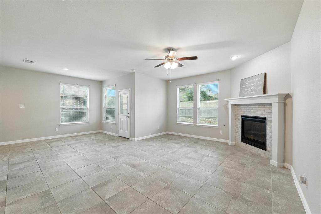 Unfurnished living room with a brick fireplace, ceiling fan, and light tile patterned flooring