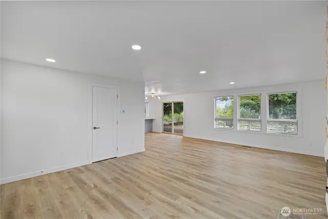 a view of empty room with wooden floor and windows