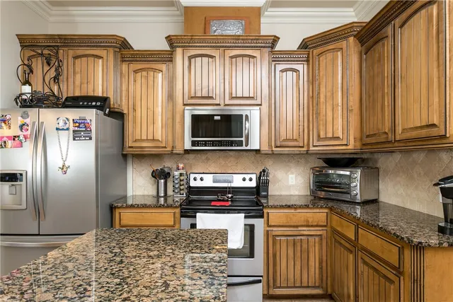 a kitchen with stainless steel appliances granite countertop a refrigerator a stove and a sink