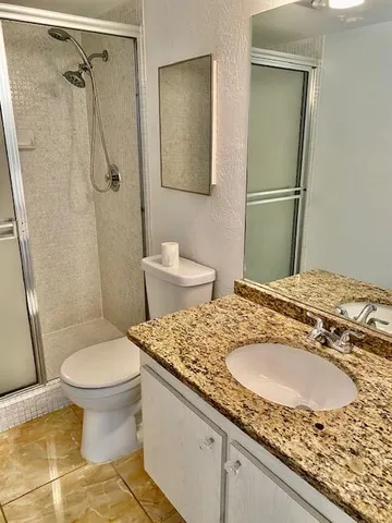 a bathroom with a granite countertop sink toilet and shower