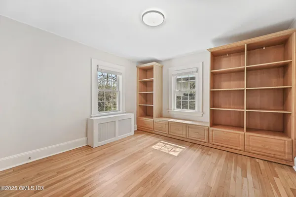 a view of an empty room with a window and wooden floor