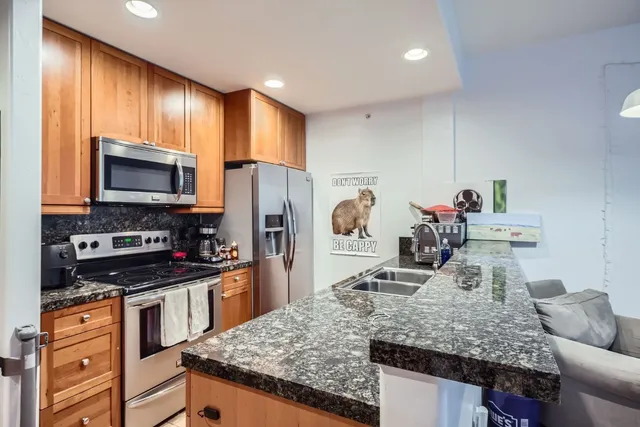 a kitchen with stainless steel appliances granite countertop a sink stove microwave and refrigerator