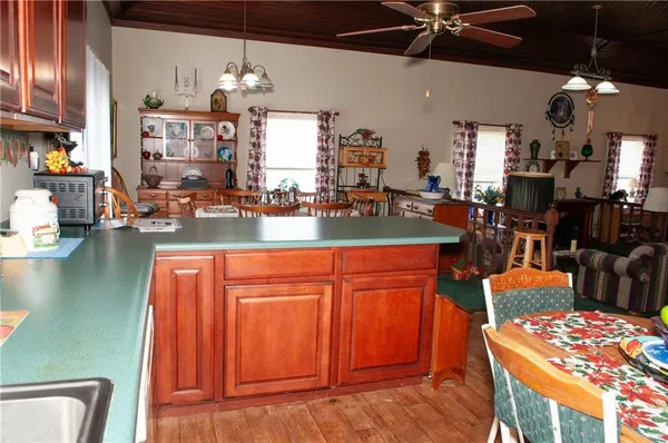 a kitchen with stainless steel appliances kitchen island granite countertop a refrigerator a stove top oven a dining table and chairs with wooden floor