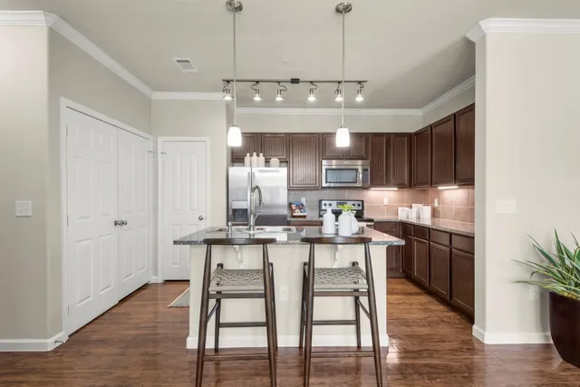 a kitchen with stainless steel appliances granite countertop a kitchen island and chairs in it