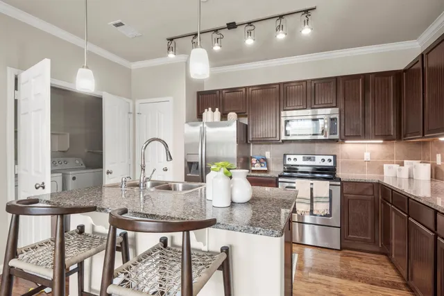 a kitchen with stainless steel appliances kitchen island granite countertop a table chairs in it and wooden floors