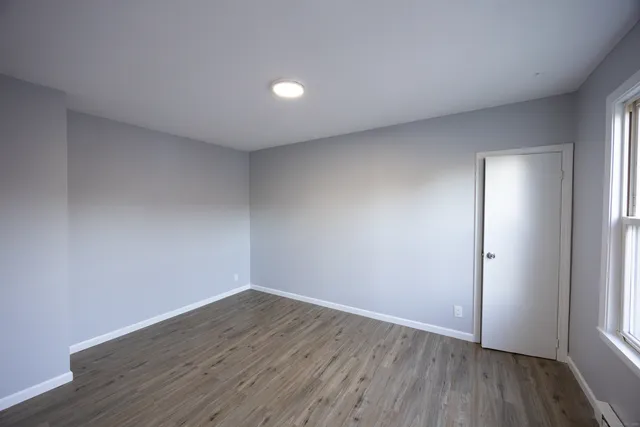 an empty room with wooden floor and window
