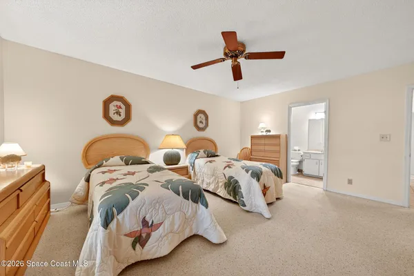 a spacious bedroom with two bed and a ceiling fan
