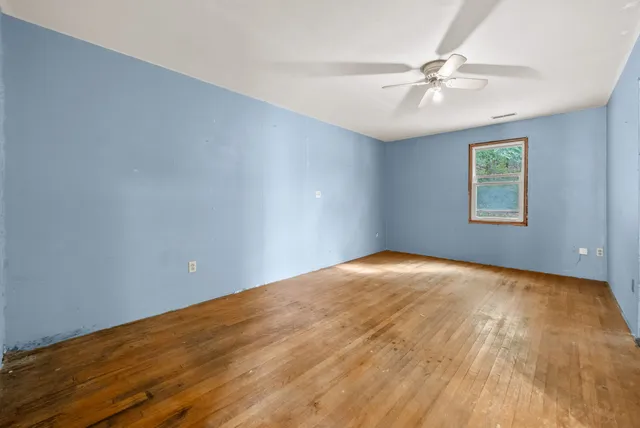 a view of an empty room and chandelier fan