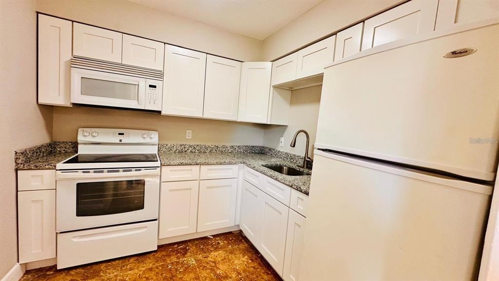 390 West Haines Boulevard, Unit 2 Lake Alfred, FL 33850 - Photo 3 of 7 a kitchen with white cabinets and white appliances