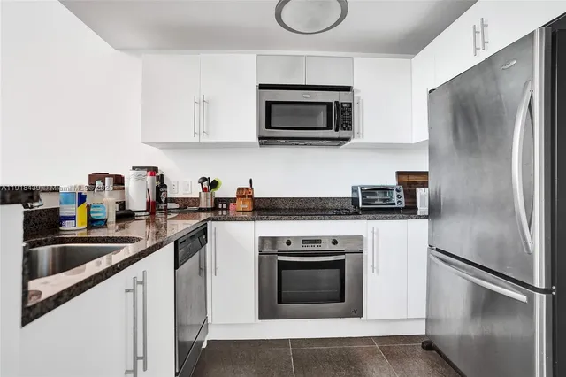a kitchen with white cabinets stainless steel appliances and a sink