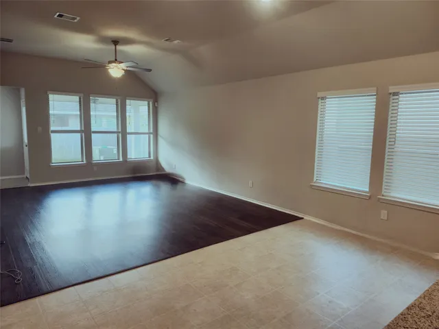 an empty room with wooden floor and windows