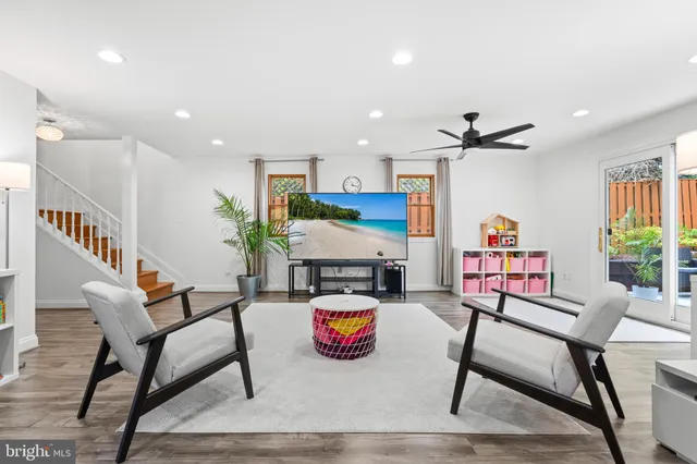 a living room with furniture kitchen view and a wooden floor