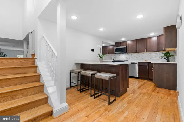 a kitchen with stainless steel appliances kitchen island granite countertop a table chairs in it and wooden floors