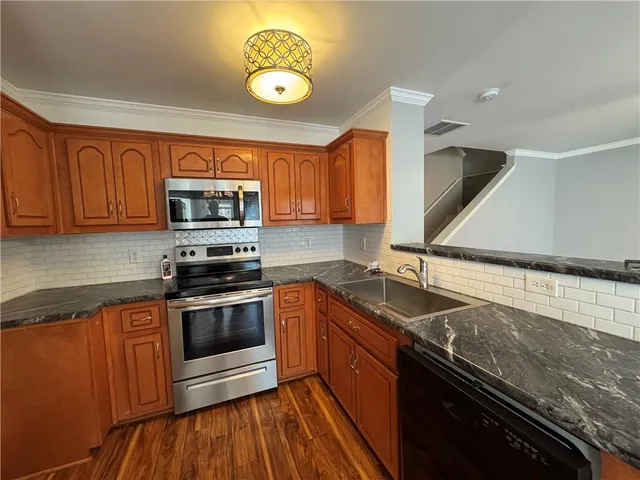 a kitchen with granite countertop a sink stainless steel appliances and cabinets
