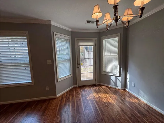 an empty room with wooden floor chandelier fan and windows