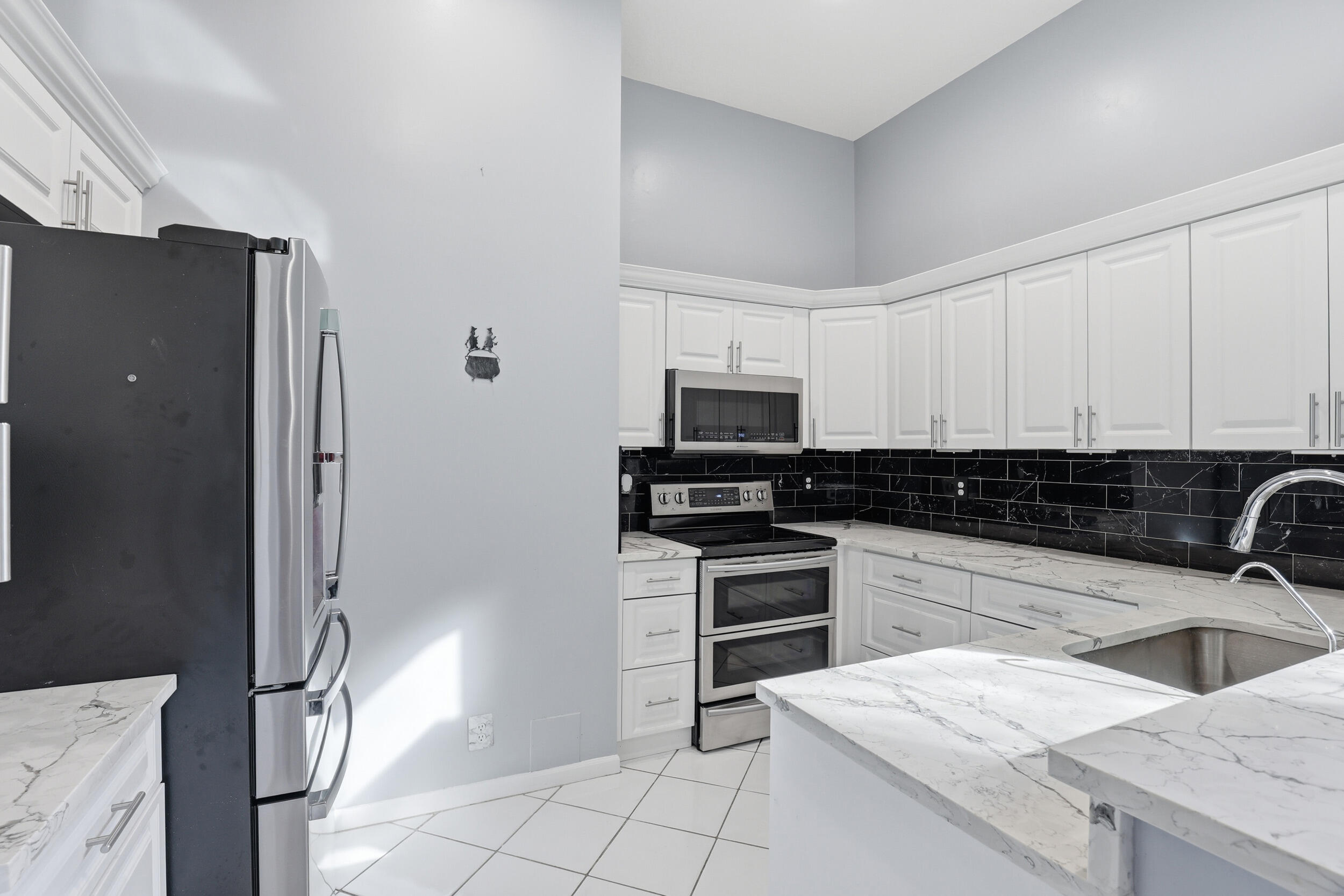 5405 Monterey Circle, Unit G Delray Beach, FL 33484 - Photo 12 of 72 a kitchen with stainless steel appliances granite countertop a sink stove and refrigerator