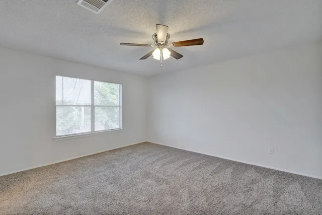 an empty room with a window and a fan