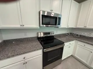 a kitchen with white cabinets and black appliances