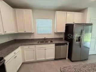 a kitchen with stainless steel appliances granite countertop a refrigerator a stove a sink and white cabinets