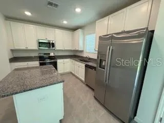 a kitchen with stainless steel appliances granite countertop a refrigerator a stove a sink and a microwave