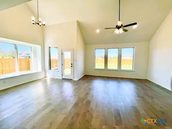 a view of an empty room with a window and wooden floor