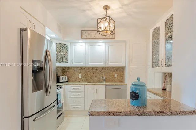 a kitchen with stainless steel appliances granite countertop a refrigerator a stove and a sink with wooden floor