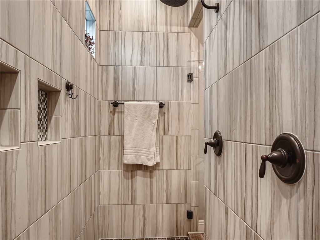 132 Huerta Road Florence, TX 76527 - Photo 17 of 40 A luxuriously tiled shower stall features integrated niches and elegant bronze fixtures.