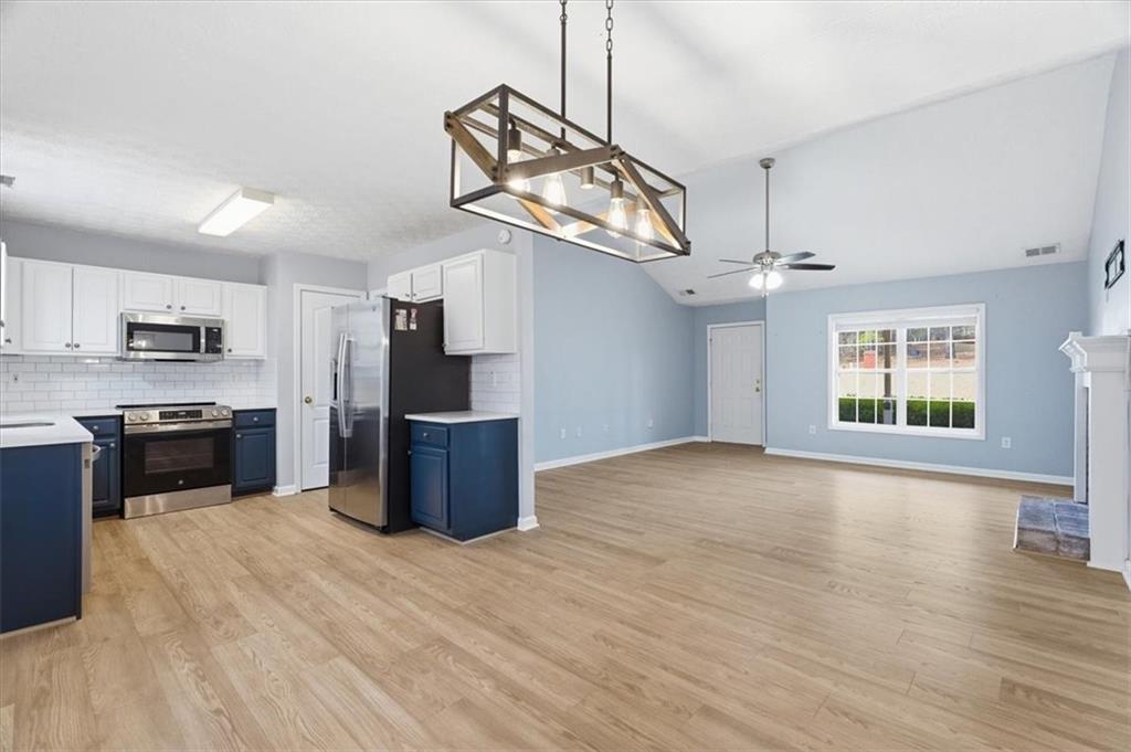 1022 Miss Amber Way Locust Grove, GA 30248 - Photo 9 of 43 a large kitchen with stainless steel appliances granite countertop a refrigerator a stove top oven a sink dishwasher and white cabinets with wooden floor