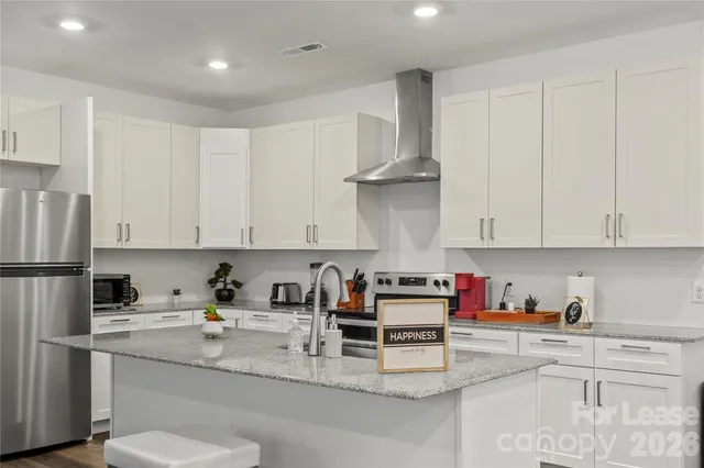 a kitchen with stainless steel appliances granite countertop a refrigerator sink and white cabinets