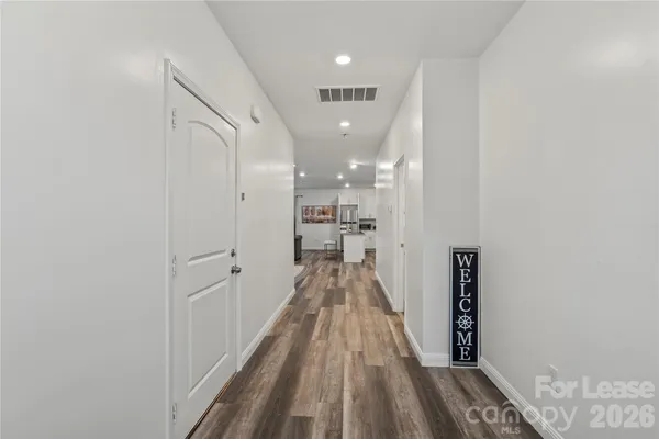 a view of a hallway with wooden floor and a bathroom
