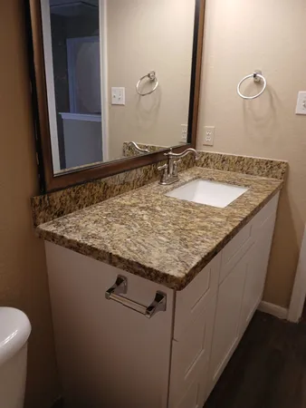 a bathroom with a granite countertop sink and a mirror