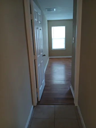 a view of a hallway with wooden floor and a window