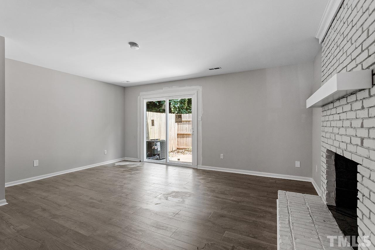 1404 Kent Road Raleigh, NC 27606 - Photo 2 of 28 a view of an empty room with wooden floor and a fireplace