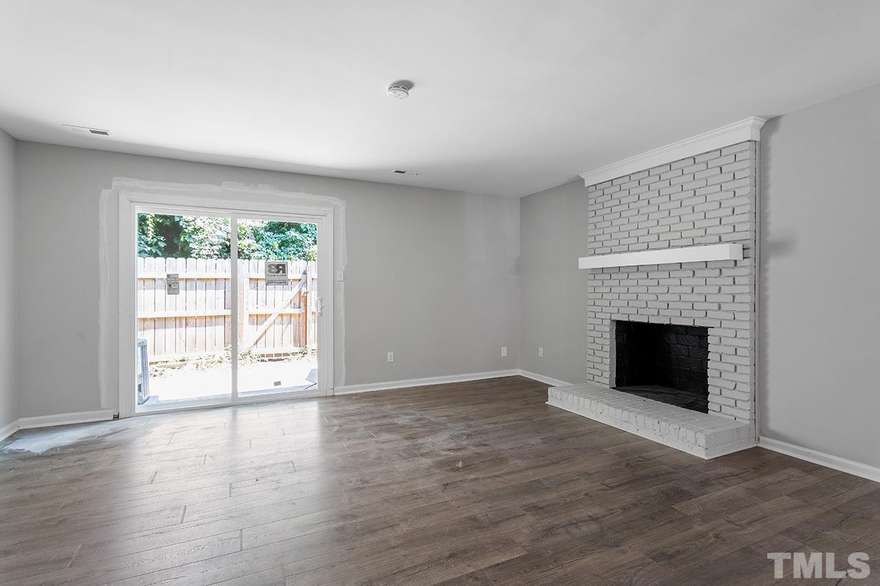 1404 Kent Road Raleigh, NC 27606 - Photo 3 of 28 an empty room with wooden floor fireplace and windows