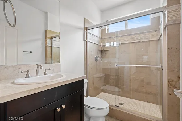 a bathroom with a shower sink vanity mirror and toilet